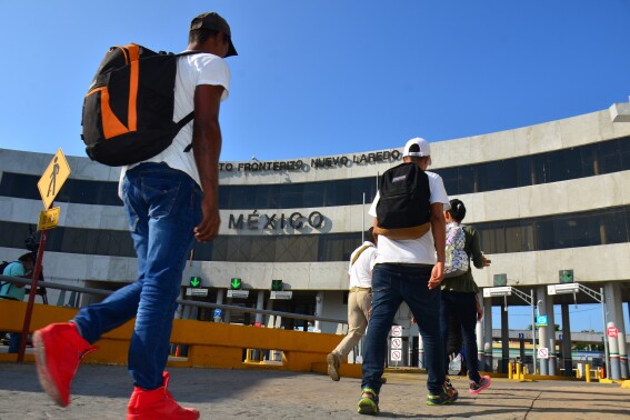 U.S. asylum-seekers being returned by U.S. authorities under the so-called Remain in Mexico program are escorted by a Mexican migration agent as they walk back into Nuevo, Laredo Mexico, across the international bridge from Laredo, Texas, Wednesday, July 10, 2019. The Biden administration has stopped taking appointments via its mobile phone app from asylum seekers in a notoriously dangerous and corrupt Mexican border city amid signs migrants who used it were being targeted for extortion.(AP Photo/Salvador Gonzalez)