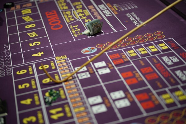 FILE - A stack of hundred-dollar bills sits on a craps table in the casino on the opening night of the Mohegan Sun Casino at Virgin Hotels Las Vegas, Thursday, March 25, 2021, in Las Vegas. The firing of Los Angeles Dodgers star Shohei Ohtani's interpreter and close friend after allegations of illegal gambling and theft from the Japanese baseball player is shining renewed attention on compulsive gambling. The National Council on Problem Gambling describes it as gambling that is damaging to a person or their family, often disrupting their daily life and career. (AP Photo/John Locher, File)