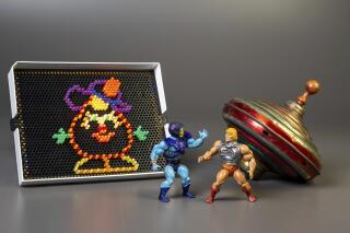This undated photo provided by The Strong Museum shows the three toys inducted into the National Toy Hall of Fame on Nov. 10, 2022, in Rochester, N.Y. Masters of the Universe, Lite-Brite and the top were chosen from among 12 finalists for the annual honor, which recognizes toys that have inspired creative play and lasting popularity. (Courtesy of The Strong Museum via AP)