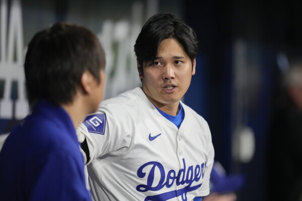 Los Angeles Dodgers' designated hitter Shohei Ohtani, right, chats with his interpreter during the first innings of an exhibition game between Team Korea and the Los Angeles Dodgers at the Gocheok Sky Dome in Seoul, South Korea, Monday, March 18, 2024. (AP Photo/Ahn Young-Joon)