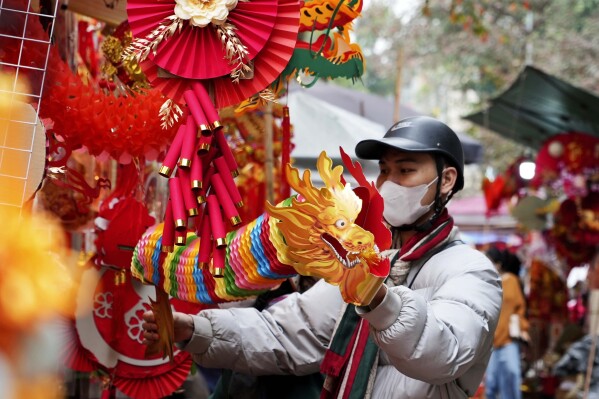 A man holds up a dragon decoration in a traditional Lunar New Year market in Hanoi, Vietnam Thursday, Feb. 8, 2024. Vietnam is preparing to welcome the Lunar New Year of the Dragon, the most popular festive event of the year. (AP Photo/Huy Han)