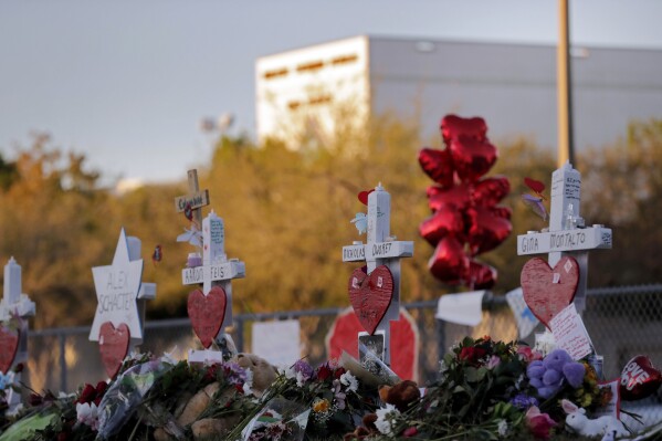 FILE- A memorial is made outside the Marjory Stoneman Douglas High School where 17 students and faculty were killed in a mass shooting in Parkland, Fla, Feb. 19, 2018. The re-enactment of the shooting at the school will take place early Aug. 2023, as part of a civil lawsuit and will use live ammunition. (AP Photo/Gerald Herbert, File)