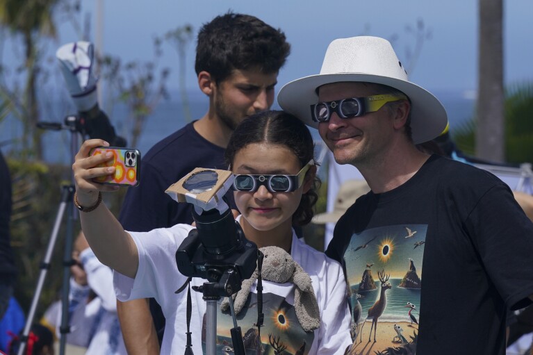 People take selfies as they watch and photograph a total solar eclipse in Mazatlan, Mexico, Monday, April 8, 2024. (AP Photo/Fernando Llano)