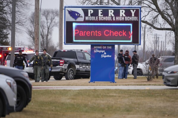 FILE - Police respond to Perry High School in Perry, Iowa., Jan. 4, 2024. Teachers and staff in the rural Iowa district where the deadly school shooting took place could get bonuses if they don't quit their jobs under a new bill approved by lawmakers and sent to the governor. (AP Photo/Andrew Harnik, file)
