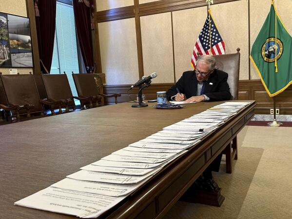 Washington Gov. Jay Inslee signs bills at the Washington State Capitol, Tuesday, May 9, 2023, in Olympia, Wash. One of those bills was Senate Bill 5599, which was designed to protect young people seeking reproductive health services or gender-affirming care. (AP Photo/Ed Komenda)