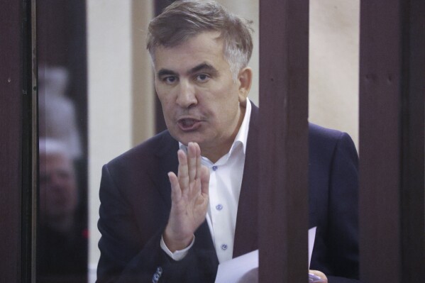 Former Georgian President Mikheil Saakashvili who was convicted in absentia of abuse of power during his presidency and arrested upon his return from exile, gestures speaking from a defendant's dock during a court hearing in Tbilisi, Georgia, Thursday, Dec. 2, 2021. . (Irakli Gedenidze/Pool Photo via AP, File)