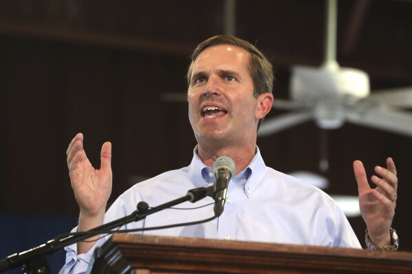 FILE - Gov. Andy Beshear speaks at the annual St. Jerome Fancy Farm Picnic in Fancy Farm, Ky., on Aug. 5, 2023. Beshear on Wednesday, Aug. 9, proposed another round of pay raises for Kentucky State Police troopers and bolstered training for law officers as part of his latest budget proposals to bolster public safety, coming amid a sharp focus on crime rates in his bid to win a second term. (Scott Utterback/Courier Journal via AP, File)