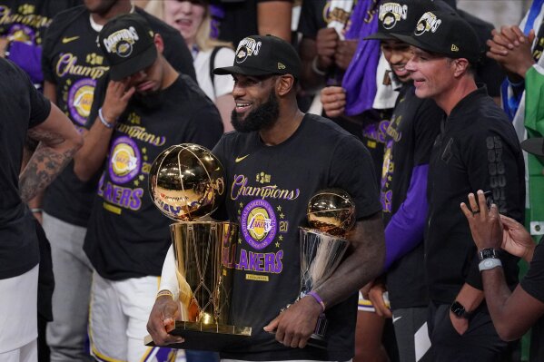 FILE - In this Oct. 11, 2020, file photo, Los Angeles Lakers' LeBron James (23) holds the trophies as he celebrates with his teammates after the Lakers defeated the Miami Heat 106-93 in Game 6 of basketball's NBA Finals in Lake Buena Vista, Fla. James was announced Saturday, Dec. 26,  as the winner of The Associated Press’ Male Athlete of the Year award for a record-tying fourth time.  (AP Photo/Mark J. Terrill, File)