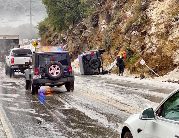 In this Saturday, Jan. 23, 2021, photo provided by the California Highway Patrol-West Valley, authorities work the scene of an accident after a hail storm on Malibu Canyon Road in Malibu, Calif. A hail storm struck the Santa Monica Mountains on Saturday, prompting the California Highway Patrol to warn drivers to slow down after officers responded to a few rollover accidents on Malibu Canyon. Up to a foot of snow fell in Southern California's mountains as the first in a series of storms move through California, bringing real winter weather after weeks of sporadic rain that has done little to ease drought. (California Highway Patrol via AP)