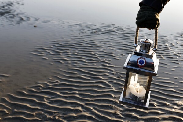 A re enactor holds a lantern during a ceremony at Utah Beach near Saint-Martin-de-Vareville Normandy, Thursday, June 6, 2024. World War II veterans from across the United States as well as Britain and Canada are in Normandy this week to mark 80 years since the D-Day landings that helped lead to Hitler's defeat. (AP Photo/Jeremias Gonzalez)