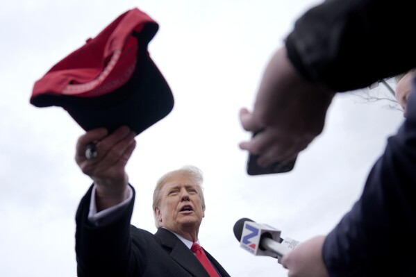 El candidato presidencial republicano, el expresidente Donald Trump, entrega un sombrero firmado durante un acto de campaña en Londonderry, NH, el martes 23 de enero de 2024. (Foto AP/Matt Rourke)