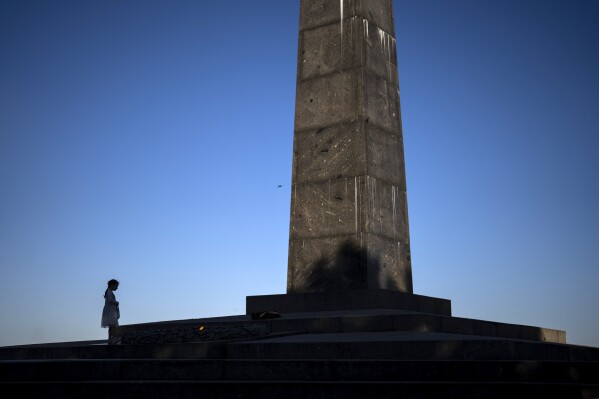 A young girl stands next to an eternal flame burning of the Unknown Soldier monument in Kyiv, Ukraine, Tuesday, April 30, 2024. (AP Photo/Francisco Seco)