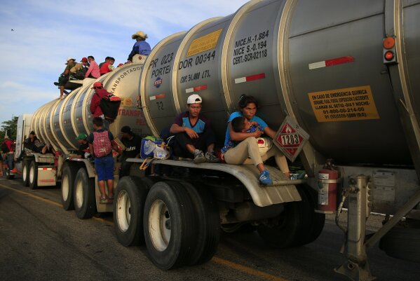 
              A woman holding her baby hitches a ride on the fender of a tanker in Niltepec, Mexico, Tuesday, Oct. 30, 2018. The caravan of thousands of migrants is continuing its slow advance, setting off through Mexico's narrow, windy isthmus for the Oaxaca state city of Juchitan, which was devastated by an earthquake in September last year. (AP Photo/Rebecca Blackwell)
            