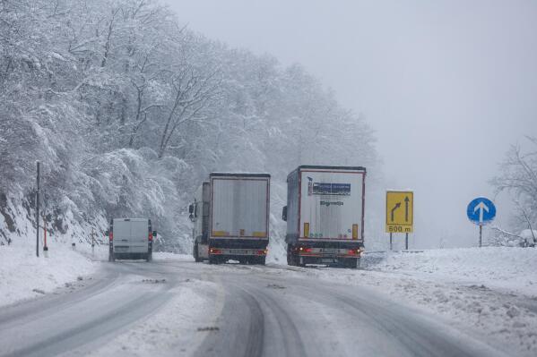 Trucks drive on a snow covered road in Kocevje, near Ljubljana Slovenia, Monday, Sept. 23, 2023. A snow storm with gust winds has hampered traffic on a key highway in Slovenia on Monday and left parts of the country temporarily without electricity. (AP Photo)