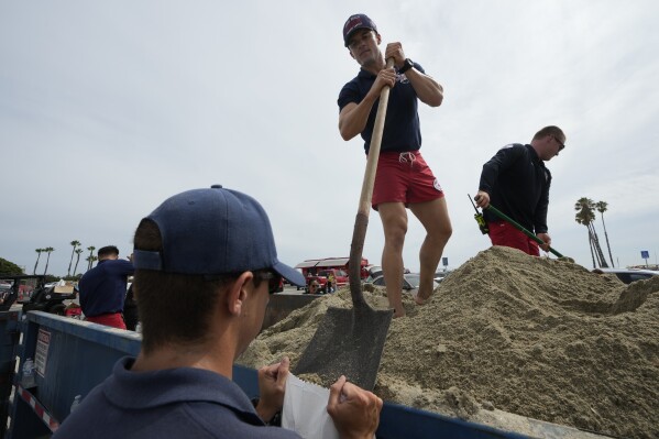 Long Beach lifeguards fill up sandbags for residents ahead of Hurricane Hilary, in Long Beach, Calif., Saturday, Aug. 19, 2023. (AP Photo/Damian Dovarganes)