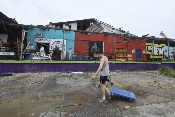 FILE - People walk past a damaged building in Tallahassee, Fla., May 10, 2024, after three tornadoes hit the city and surrounding areas. Tallahassee Mayor John Dailey said on Friday, May 31, 2024 that recovery has cost Florida’s capital city $50 million so far as it still seeks federal aid.(AP Photo/Phil Sears, file)