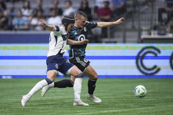 Vancouver Whitecaps' Bjorn Inge Utvik, front left, defends against Minnesota United's Robin Lod during the first half of an MLS soccer match, in Vancouver, on Wednesday, May 28, 2025. (Darryl Dyck/The Canadian Press via AP)