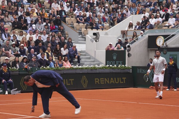 The chair umpire checks a mark on the clay as France's Arthur Fils looks on, during his first round match of the French Tennis Open against Chile's Nicolas Jarry, at the Roland-Garros stadium, in Paris, Monday, May 26, 2025. (AP Photo/Lindsey Wasson)