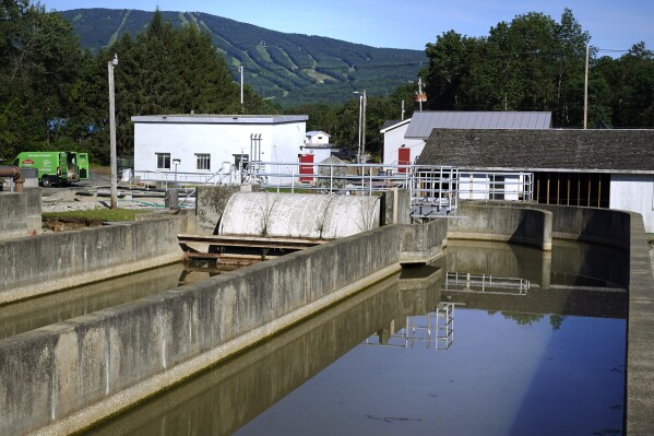 The Okemo ski resort is visible in the distance from a defunct wastewater treatment tank, Wednesday, Aug. 2, 2023, in Ludlow, Vt. July’s floodwaters washed sewage from the ditches into the river, and only one has been repaired and is functioning. (AP Photo/Charles Krupa)