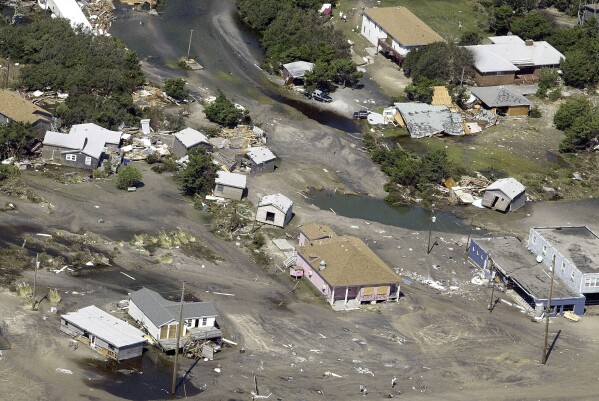 FILE - Homes are scattered around flood waters in Hatteras, N.C., Sept. 19, 2003, after flooding from Hurricane Isabel. (AP Photo/Chuck Burton, File)