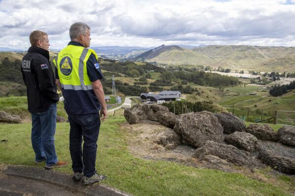 New Zealand Prime Minister Chris Hipkins, left, and Hawke's Bay Civil Defence and Emergency Management Group Controller Ian McDonald survey cyclone Gabrielle damage to the Esk Valley, north of Napier, New Zealand, Friday, Feb. 17, 2023. The death toll from New Zealand's cyclone reached eight on Friday with more than 4,500 people still unaccounted for four days after the nation's most destructive weather event in decades brought widespread flooding, landslides and power outages, the prime minister said. (Mark Mitchell/New Zealand Herald via AP)
