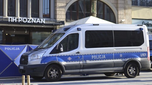 Un vehículo policial permanece estacionado frente a un restaurante en el que dos hombres murieron a balazos en una popular zona turística, el domingo 16 de julio de 2023, en Poznan, Polonia. (AP Foto/KWP Poznan)