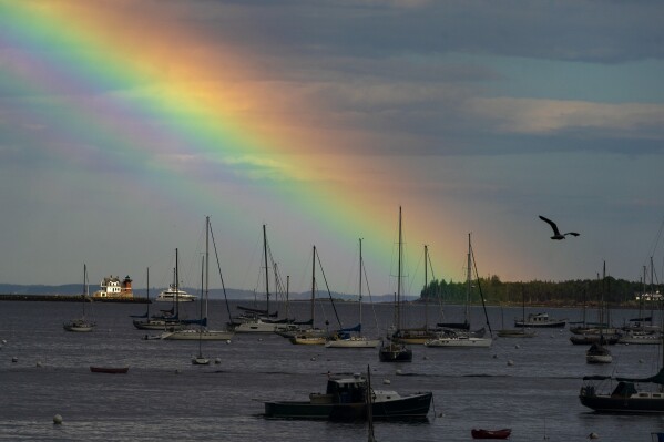 A rainbow colors the sky beyond the Rockland Harbor Breakwater Lighthouse following a brief rainstorm, Tuesday, Aug. 1, 2023, in Rockland, Maine. (AP Photo/Robert F. Bukaty)