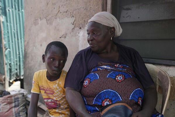 Funmilayo Kotun, 66-years-old, a malaria patient is photographed with her grandson Ayomide Kotun, outside her house in Makoko neighbourhood of Lagos, Nigeria, Saturday, April 20, 2024. (AP Photo/Sunday Alamba)