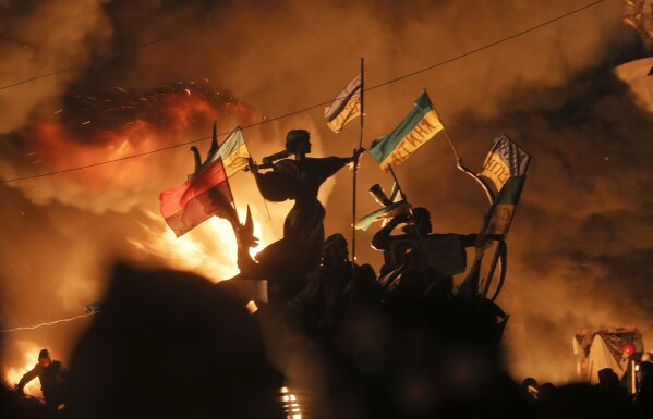 
              FILE - In this Feb. 18, 2014 file photo, monuments to Kiev's founders burn as anti-government protesters clash with riot police in Kiev's Independence Square, the epicenter of the country's then unrest, Kiev, Ukraine. Russian border guards opened fire on three Ukrainian vessels late Sunday, Nov. 25, 2018 in the Kerch Strait near the Russia-occupied Crimean peninsula, raising the prospect of a full-scale military confrontation between the two neighbors. The incident comes on the back of a four-and-a-half year long proxy conflict in eastern Ukraine. (AP Photo/Efrem Lukatsky, File)
            