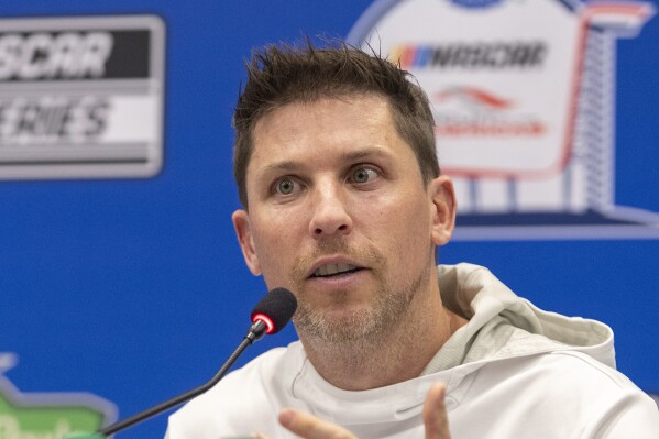 FILE - Co-owner Denny Hamlin speaks about his team winning a NASCAR Cup Series auto race at Circuit of the Americas, Sunday, March 26, 2023, in Austin, Texas. A new NASCAR season begins with rivals attempting to dethrone Team Penske after two years atop the Cup Series, all while a compelling off-track battle rages on over revenue sharing that threatens to overshadow the competition. Hamlin, the three-time Daytona 500 winner for Joe Gibbs Racing and co-owner alongside Michael Jordan of 23XI Racing, is most vocal on the issue. (AP Photo/Stephen Spillman, File)