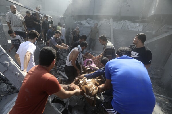 Palestinians carry an injured woman after being rescued from under the rubble of a destroyed building following an Israeli airstrike in Bureij refugee camp, Gaza Strip, Thursday, Nov. 2, 2023. (AP Photo/Mohammed Dahman)