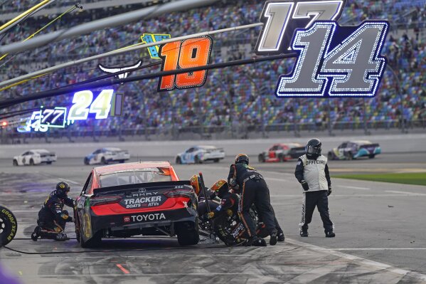 Martin Truex Jr.'s crew repairs damage to his car during a pit stop in the NASCAR Cup Series road course auto race at Daytona International Speedway, Sunday, Feb. 21, 2021, in Daytona Beach, Fla. (AP Photo/John Raoux)