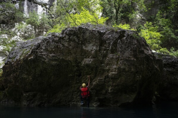 A tourist climbs a canyon wall along the Verdon Gorge in southern France, Monday, June 19, 2023. Human-caused climate change is lengthening droughts in southern France, meaning the reservoirs are increasingly drained to lower levels to maintain the power generation and water supply needed for nearby towns and cities. It's concerning those in the tourism industry, who are working out how to keep their lakeside businesses afloat. (AP Photo/Daniel Cole)