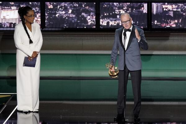 Michael Keaton, right, accepts the Emmy for outstanding lead actor in a limited or anthology series or movie for "Dopesick" at the 74th Primetime Emmy Awards on Monday, Sept. 12, 2022, at the Microsoft Theater in Los Angeles. Oprah Winfrey looks on from stage left. (AP Photo/Mark Terrill)