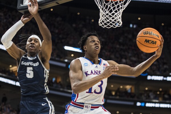Kansas guard Elmarko Jackson (13) lays the ball up while guarded by Samford guard A.J. Staton-McCray (5) during the first half of a first-round college basketball game in the NCAA Tournament in Salt Lake City, Thursday, March 21, 2024. (AP Photo/Isaac Hale)