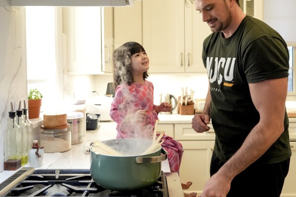 Damon LaSalle cooks pasta for the family while talking with his youngest daughter, Friday, Feb. 21, 2025, in Warren, N.J. (AP Photo/Julia Demaree Nikhinson)