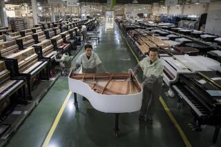 FILE - In this photo released by Xinhua News Agency, workers transfer a half-assembled piano at a production factory of Parsons Music Corporation in Yichang, central China's Hubei Province, on Nov. 23, 2021. Chinese manufacturing’s recovery from anti-virus shutdowns faltered in July as activity sank, a survey showed Sunday, July 31, 2022, adding to pressure on the struggling economy in a politically sensitive year when President Xi Jinping is expected to try to extend his time in power. (Xiao Yijiu/Xinhua via AP, File)