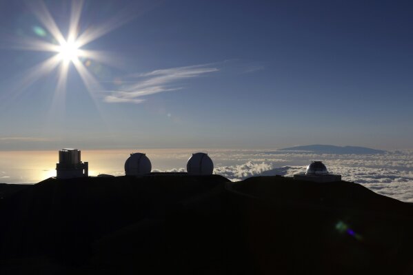 FILE - In this July 14, 2019, file photo, the sun sets behind telescopes at the summit of Mauna Kea. A senior University of Hawaii official says losing the Thirty Meter Telescope could mean losing billions of dollars in research funding over the next few decades. University of Hawaii Vice President for Research and Innovation Vassilis Syrmos told the Honolulu Star-Advertiser not building the advanced telescope on the summit of Mauna Kea could impair the school's ability to attract research dollars. (AP Photo/Caleb Jones, File)