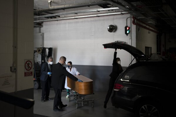 In this April 14, 2020, photo, workers prepare to transport a coffin at the Sancho de Avila funeral home in Barcelona, Spain. Since a state of emergency was declared on March 14 in the country, funeral homes must follow strict measures to avoid further contagion. Now, infected corpses cannot be removed from their sealed body bags and are placed straight into coffins. (AP Photo/Felipe Dana)