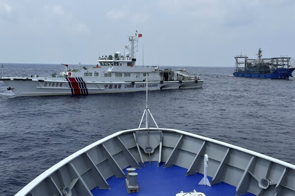 FILE - A Chinese coast guard ship, left, with a Chinese militia vessel, right, blocks Philippine coast guard ship, BRP Sindangan as it tried to head towards Second Thomas Shoal at the disputed South China Sea during rotation and resupply mission on Oct. 4, 2023. A Philippine navy patrol ship was shadowed by Chinese forces near a disputed shoal in the South China Sea, sparking a fresh exchange of accusations and warnings between the Asian neighbors Tuesday, Oct. 31. (AP Photo/Joeal Calupitan, File)