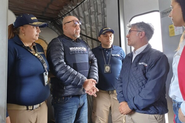 In this photo released by the Colombian Immigration agency, migration officials meet former Colombian paramilitary leader, Salvatore Mancuso, at the gate of the plane at El Dorado International Airport in Bogota, Colombia, Tuesday, Feb. 27, 2024, upon arrival from the U.S. which deported him after he served time for drug trafficking. (Colombian Immigration Agency via AP)