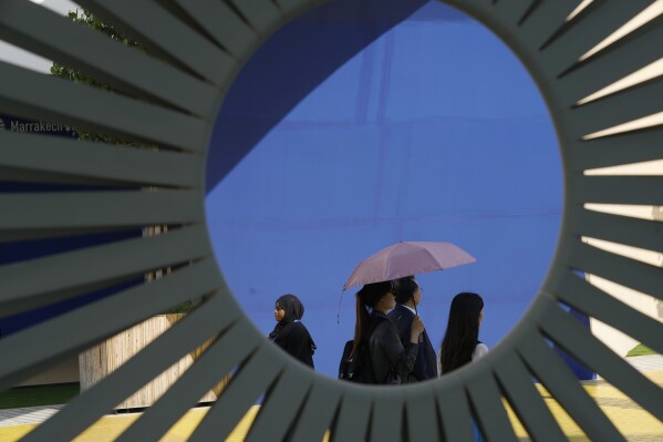 A woman walks with an umbrella to shield herself from the sun during the COP28 U.N. Climate Summit, Dec. 9, 2023, in Dubai, United Arab Emirates. (AP Photo/Peter Dejong)