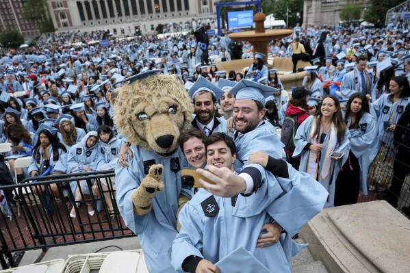 Students will pose with the person who dressed up the lion mascot Rolle at a ceremony that began on the main campus of Columbia University in Manhattan on Wednesday, May 21, 2025 in New York. (Jeenah Moon/Pool Photo via AP)