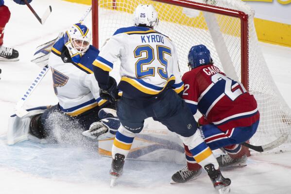 Montreal Canadiens' Cole Caufield (22) scores against St. Louis Blues goaltender Ville Husso as Blues' Jordan Kyrou looks for a rebound during overtime period NHL hockey game action in Montreal, Thursday, Feb. 17, 2022. (Graham Hughes/The Canadian Press via AP)