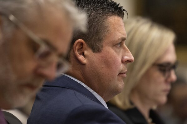 Auburn Police Officer Jeffrey Nelson, center, is flanked by two of his defense attorneys as Nelson's murder trial gets underway, Thursday, May 16, 2024 in Kent, Wash. On the left is Tim Leary, to the right is Emma Scanlan. Nelson is charged with murder in the death of a 26-year-old man outside a convenience store. (Ken Lambert