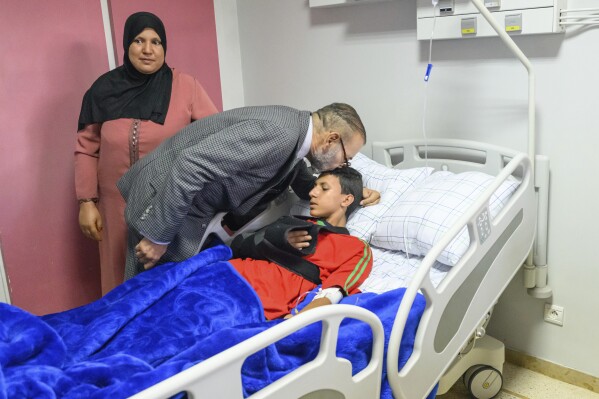 In this photo released by the Royal Palace, Morocco's King Mohammed VI, center, goes to the "Mohammed VI" University Hospital in Marrakech, Morocco. Tuesday 12, 2023. The Sovereign inquired about the state of health of the injured, victims of the painful earthquake that occurred last Friday, September 8. (Moroccan Royal Palace via AP)