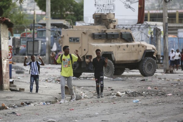 Youths raise their hands to show police they are not carrying weapons during an anti-gang operation at the Portail neighborhood in Port-au-Prince, Haiti, Thursday, Feb. 29, 2024. (AP Photo/Odelyn Joseph)