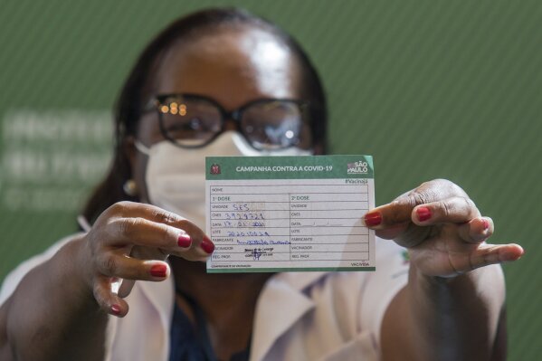 Nurse Monica Calazans, 54, shows her vaccination card after being the first Brazilian to receive the COVID-19 vaccine produced by China’s Sinovac Biotech Ltd, at the Hospital das Clinicas in Sao Paulo, Brazil, Sunday, Jan. 17, 2021. (AP Photo/Carla Carniel)