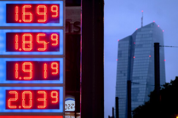 FILE - Gas prices are displayed at a gas station next to the headquarters of the European Central Bank, rear, in Frankfurt, Germany, on July 28, 2023. The inflation that has been wearing on European consumers fell sharply to 2.9% in October, its lowest in more than two years as fuel prices fell and rapid interest rate hikes from the European Central Bank took hold. (AP Photo/Michael Probst, File)