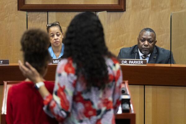 Djifa lee, a second-grade teacher at Saunders Elementary, center, stands with her daughter as she speaks in front of the Newport News School Board at the Newport News Public Schools Administration building on Tuesday, Jan. 17, 2023, in Newport News, Va. Community members spoke about issues and solutions to violence in schools following the shooting at Richneck Elementary by a six-year-old that left a teacher in critical condition. (Billy Schuerman/The Virginian-Pilot via AP)